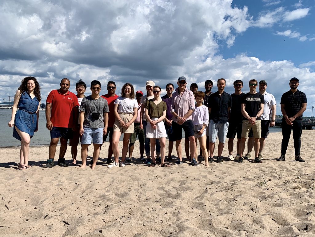 A group photo: members of the group standing on a beach during the annual summer retreat.